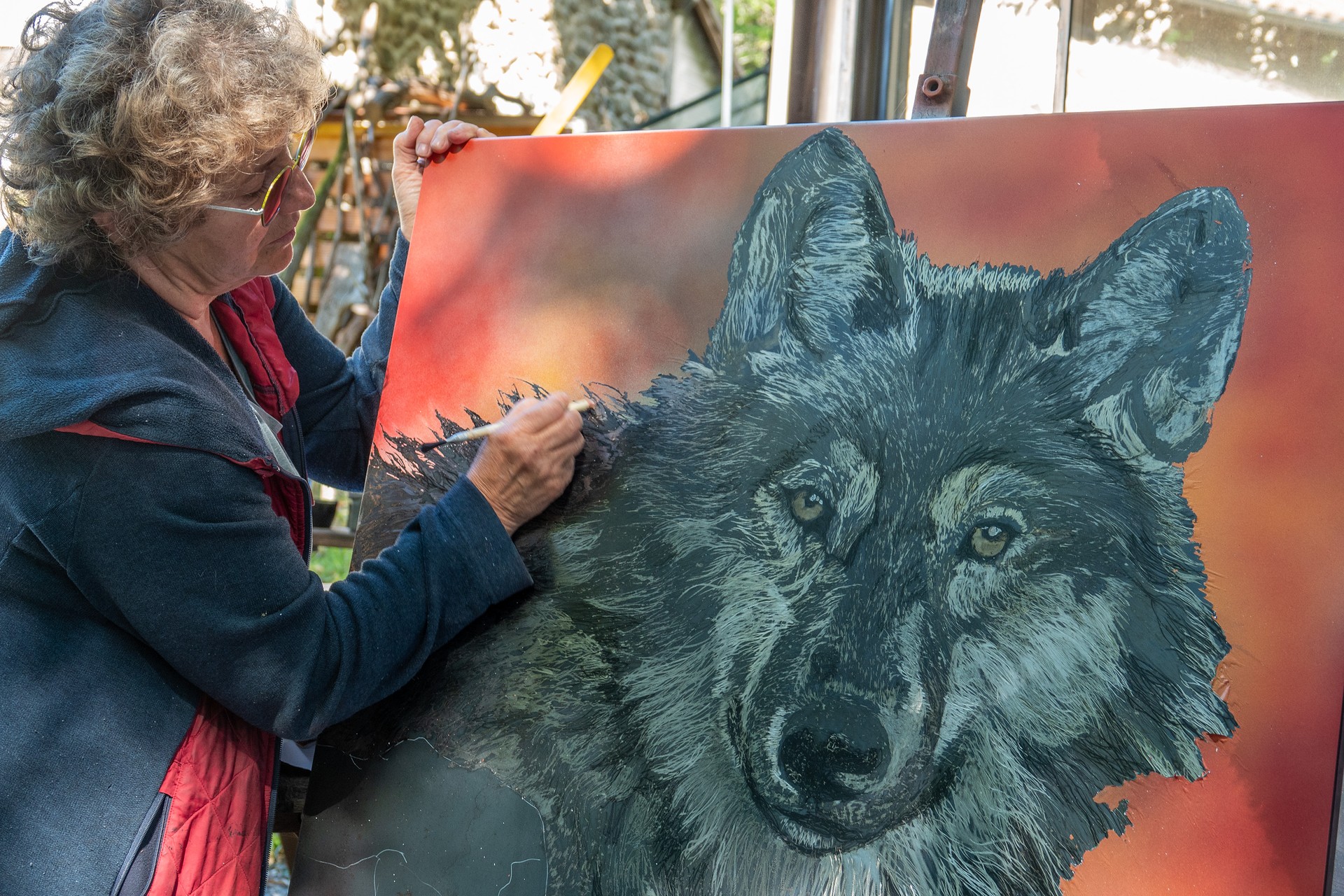 Corinne Dunand en pleine peinture d'un portrait de loup dans son atelier à Fabras en Ardèche