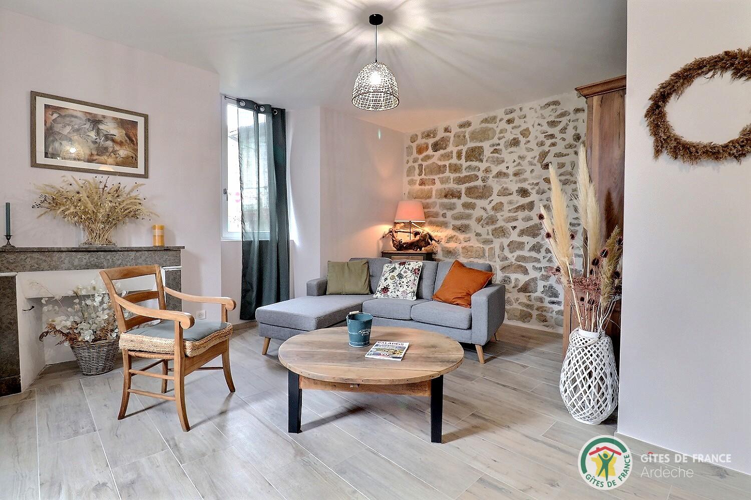 Salon avec mur en pierres apparentes, chaleureux avec canapé et TV